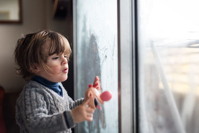 Portrait of boy looking through window