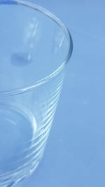 Close-up of glass over water against blue background