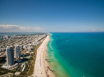 Aerial view of city by sea against blue sky