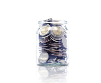 Close-up of coins in jar against white background