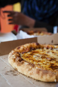 Cropped image of pizza in box against person