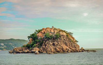 Rock formations by sea against sky