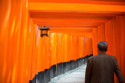 Rear view of man walking in illuminated building