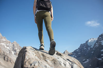 Low section of man standing on mountain against sky