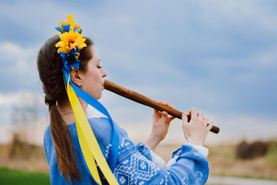 Young woman blowing bubbles while standing against sky