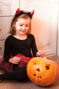 Portrait of cute girl with pumpkin on table