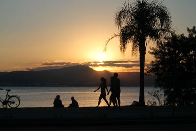 Silhouette people against lake during sunset