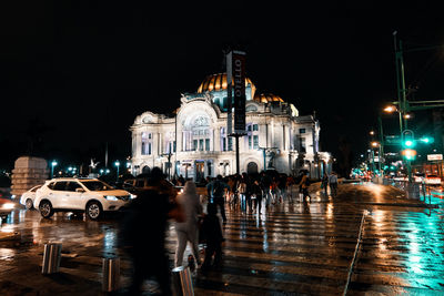 People on street against buildings at night