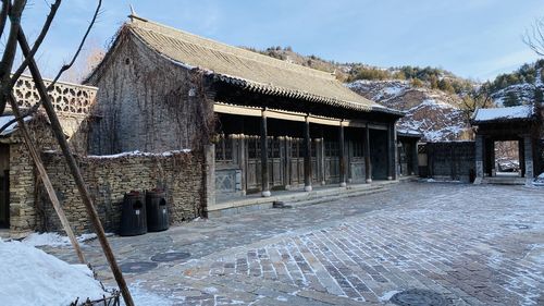 Snow covered houses by building against sky