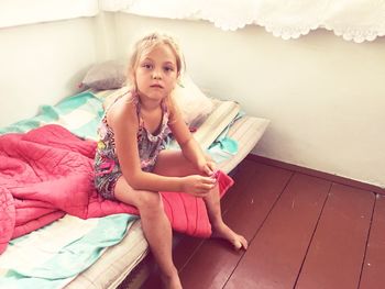 Portrait of girl sitting on bed at home