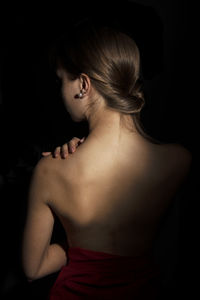 Rear view of woman standing against black background