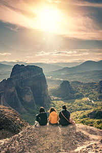 Rear view of people looking at mountains against sky