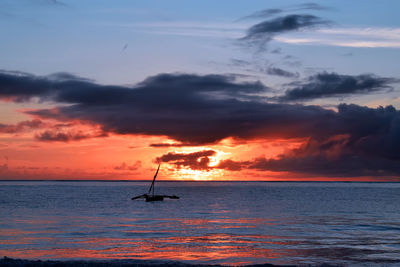 Silhouette sailboat in sea against sky during sunset