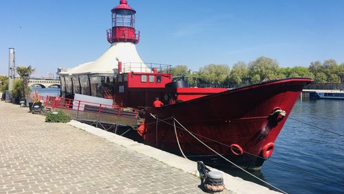 Red ship moored on sea against sky