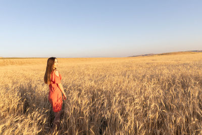 Rear view of woman standing on field against clear sky