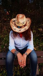 Midsection of woman wearing hat sitting outdoors