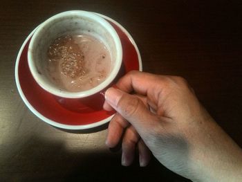 Close-up of hand holding coffee cup on table