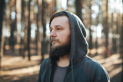 Thoughtful young man standing in forest