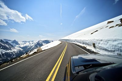 Road by mountains against sky during winter