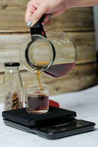 Close-up of hand pouring wine in glass on table