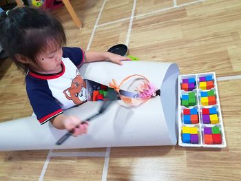 High angle view of girl playing with toy on hardwood floor at home