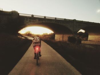 Rear view of people walking on road in tunnel