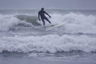 Rear view of man surfing in sea