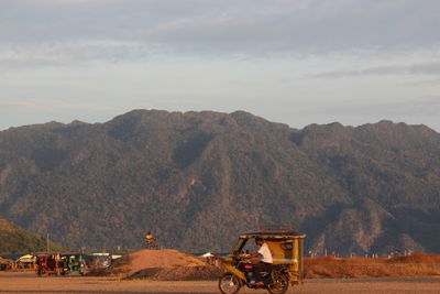 Tractor on field by mountains against sky