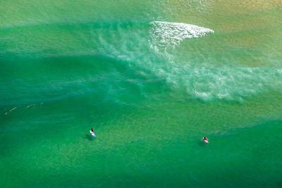 High angle view of friends paddleboarding in sea