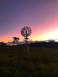 Low angle view of windmill on field against sky at sunset