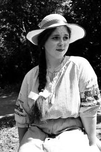 Thoughtful woman wearing hat sitting outdoors