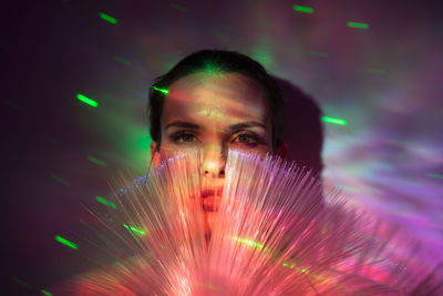 Portrait of beautiful young woman against illuminated background