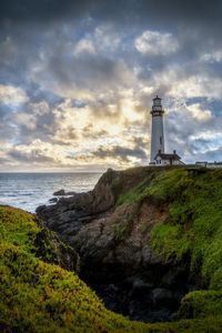 Lighthouse by sea against sky