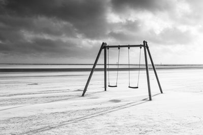 Swing on beach against sky