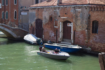 People on boat sailing in canal by city