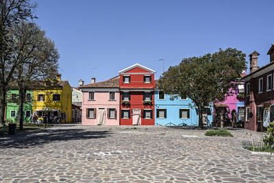 Street amidst houses and buildings against blue sky