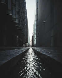 Surface level of wet footpath amidst buildings in city