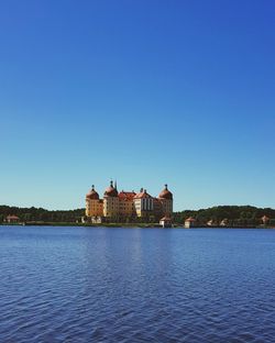 Buildings at waterfront against blue sky