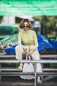 Portrait of woman wearing sunglasses sitting on seat