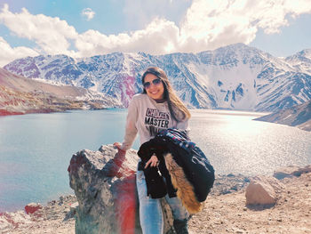 Young woman sitting on mountain against sky