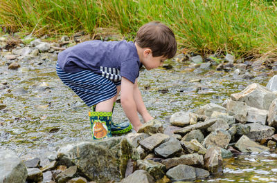 Boy standing on pebbles in water