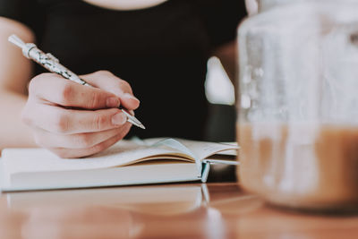 Midsection of woman reading book at home