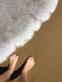 Low section of woman standing on sand at beach