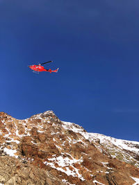 Airplane flying over snowcapped mountains against clear blue sky