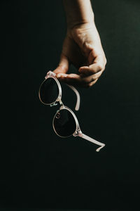 Cropped hand of person holding coffee on black background