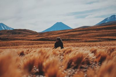 Woman sitting on field against sky