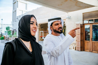 Smiling couple talking while walking on street in town