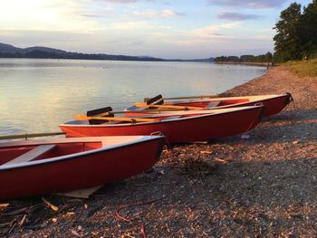 Boat moored at shore against sky during sunset