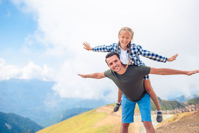 Full length of young woman jumping on mountain against sky