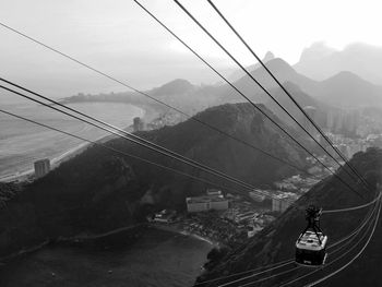 Overhead cable cars over road against sky in city